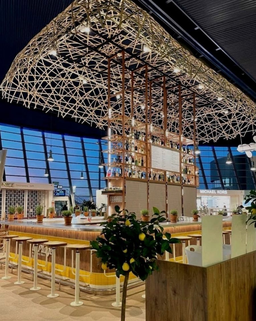 The woven rattan canopy above the bar at Bar de la Plage, Nice Côte d’Azur airport, with the terminal glazing behind