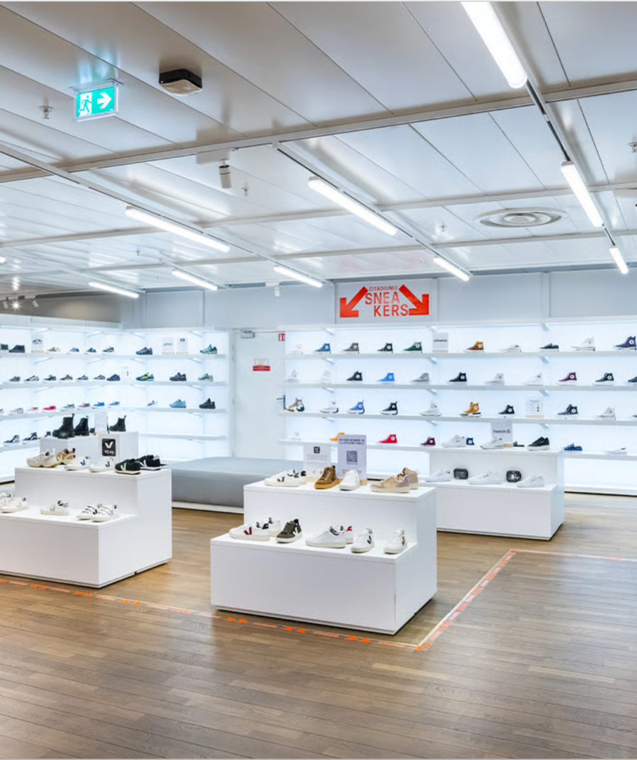 The sneaker floor at Citadium: backlit wall shelving and white display plinths on a wood floor