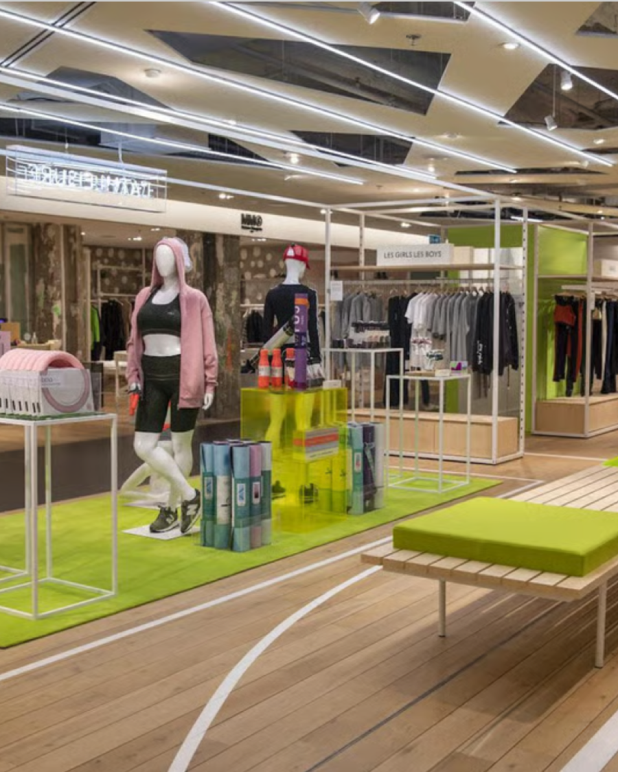 The athleisure floor at Printemps Nation: mannequins on a green running-track rug, open rails and pale timber flooring