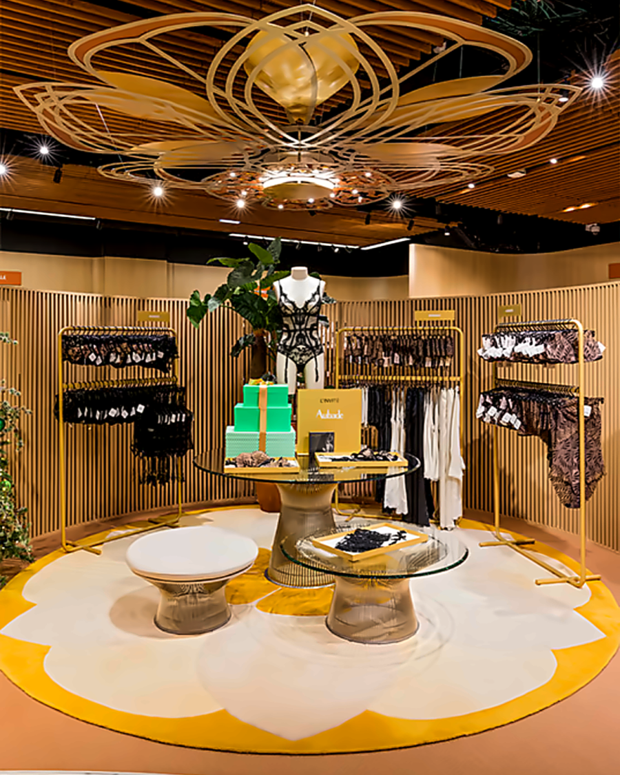 The lingerie department at Printemps Nation: a gold petal sculpture suspended over a flower-shaped rug and brass rails