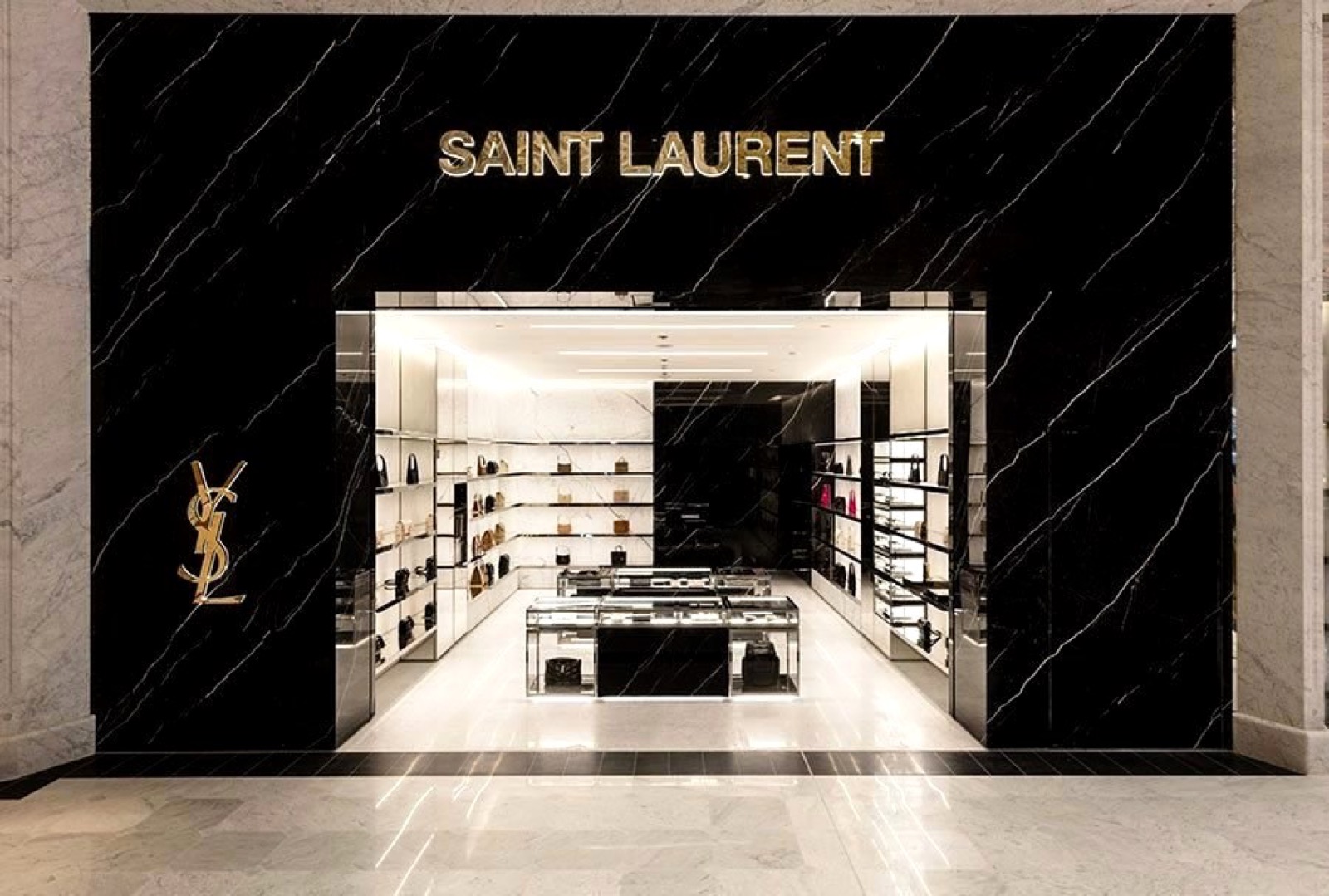 The Saint Laurent storefront at Paris CDG Terminal 1, framed in black marble with the brand’s gold signage